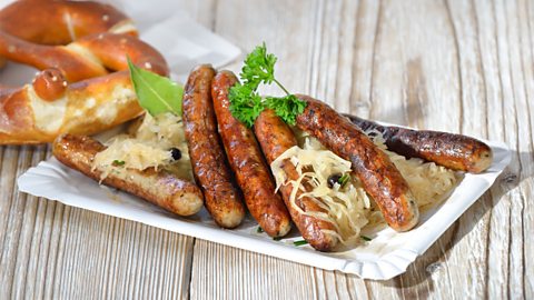 Six fried Bavarian sausages from Nuremberg - so called 'rostbratwurst' - served with sauerkraut and a pretzel