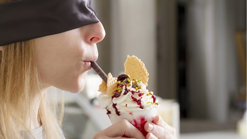 Blindfolded young woman tasting ice cream