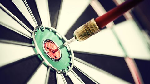 Dart arrow hitting in the target center of dartboard
