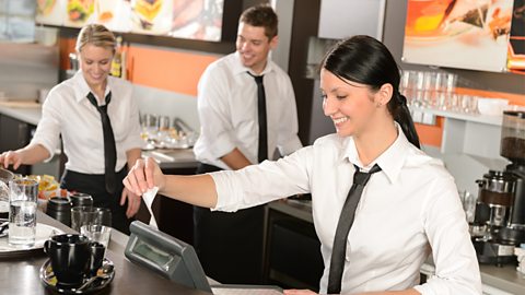 Female cashier giving receipt to colleagues working in café