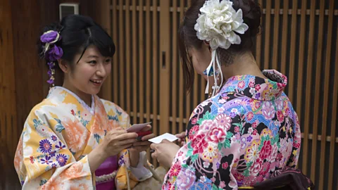 Getty Images Women wearing traditional kimono costume swap cards in Kyoto, Tokyo, Japan (Credit: Getty Images)