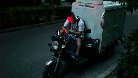 Getty Images A delivery driver checks his phone in Beijing