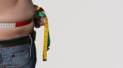 Overweight man measuring his waist