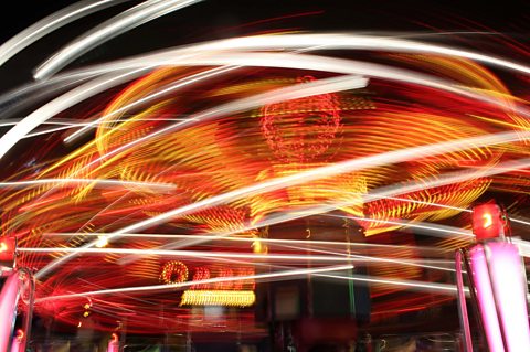 Student photograph of fairground ride with lights that have been blurred to create abstract shapes