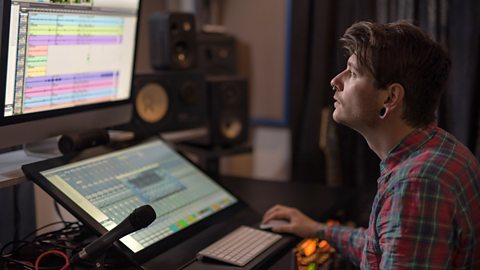 A sound designer editing at a digital mixing desk