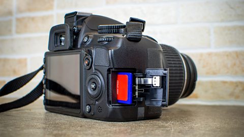 An SD card being inserted into a DSLR