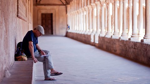 A man sitting in the foreground with cloisters in the background