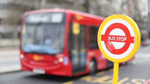 A bus stop sign with blurred out bus in the background