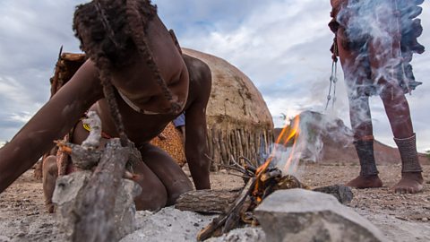 Extreme low angle shot looking up at a young girl lighting a fire