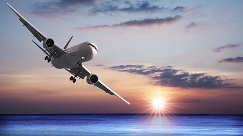 Aircraft flying over the sea at sunset