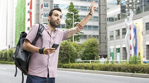 Young man holding phone hailing Uber taxi