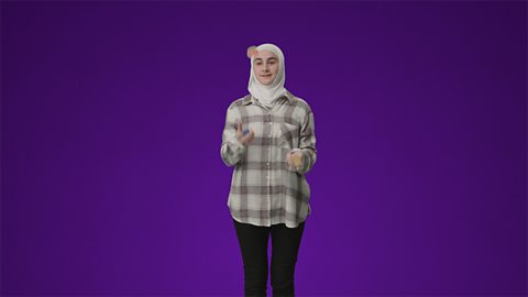 A student standing in front of a purple background juggling. They are wearing a white chequered shirt, black jeans and a white head scarf.