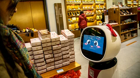 Getty Images Artificial intelligence will let robots do more complicated jobs, such as this shop assistant serving customers in Japan (Credit: Getty Images)