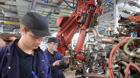 Getty Images In many factories, humans already work alongside robots - some think feelings of displacement could have knock-on effects on mental health (Credit: Getty Images)