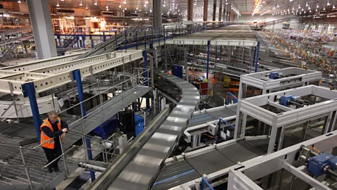 Getty Images A single worker observes the automated sorting machinery at a depot for the supermarket Sainsbury's (Credit: Getty Images)