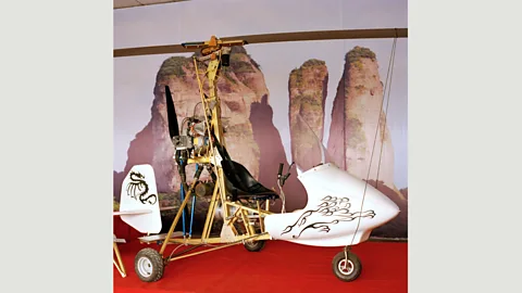 Xiaoxiao Xu Xu’s autogyro next to a poster of nearby Jianglang Mountain: “I love flying [there]… I make it to the edge of the mountain and then hover along its ridges.” (Credit: Xiaoxiao Xu)