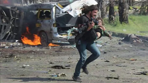 Baladi News/Muhammad Alrageb Syrian photographer Abd Alkader Habak carried a child to safety after a convoy of buses carrying evacuees from Syrian villages was bombed (Credit: Baladi News/Muhammad Alrageb)