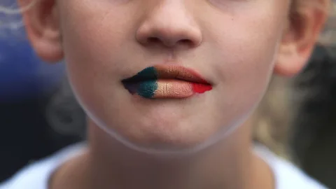 Joe Raedle/Getty Images A young woman with lips painted in the gay pride colors at the memorial for victims of the mass shooting at the Pulse nightclub in Orlando (Credit: Joe Raedle/Getty Images)
