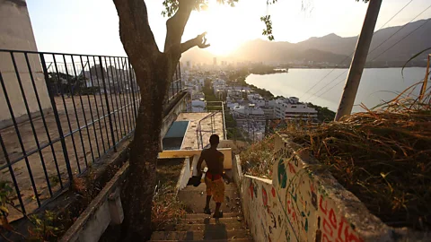 Getty Images A resident walks in the Cantagalo shantytown in Rio de Janeiro, with the wealthy Ipanema seen in the distance (Credit: Getty Images)