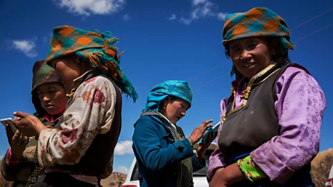 Getty Images Tibetan women use mobile phones in a village near Yamdrok Lake in Tibet (Credit: Getty Images)