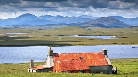 Alamy Studies show that living near the water, as at this cottage on the Isle of Lewis, is correlated with higher levels of happiness (Credit: Alamy)