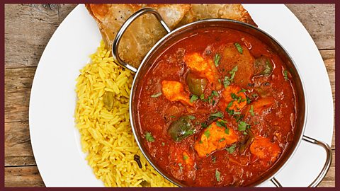 Focus image: a bowl of spicy food, rice and bread