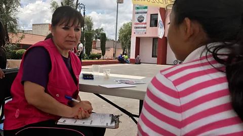 Julissa Trevino Adriana Chavez, a psychologist with the Instituto de la Mujeres, chats with 12-year-old Raquel Barrera and her parents (Credit: Julissa Trevino)