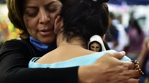 AFP/Getty Images A woman holding an image of the Virgin of Fatima comforts a relative of people who are presumed still buried under the rubble (Credit: AFP/Getty Images)