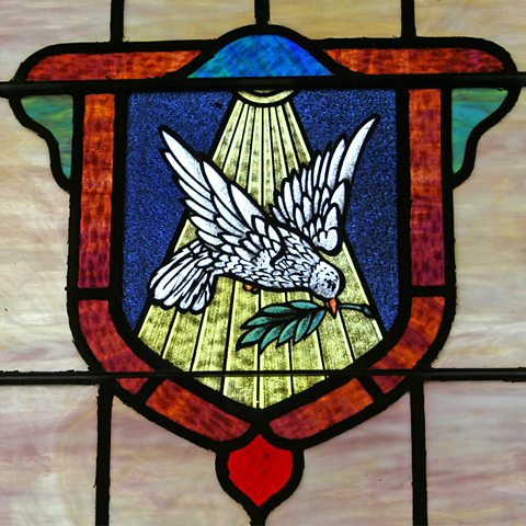 Stained glass window depicting a dove holding a branch in its beak