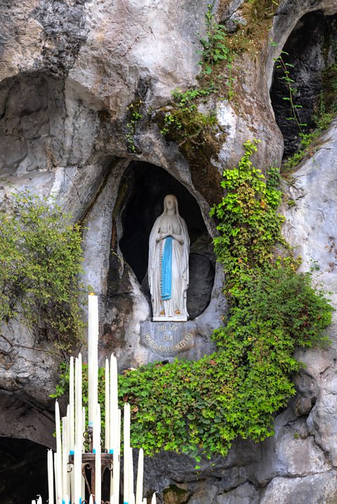 Statue of the Virgin Mary in a cave on a cliff face 