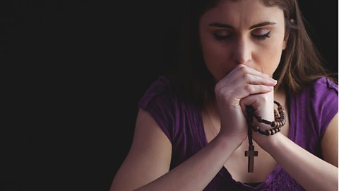 Woman praying with wooden rosary beads