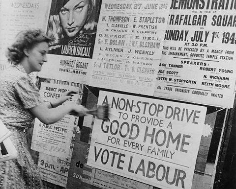 A woman plasters a poster onto a well. Text: A non-stop drive to provide a good home for every family. Vote Labour.