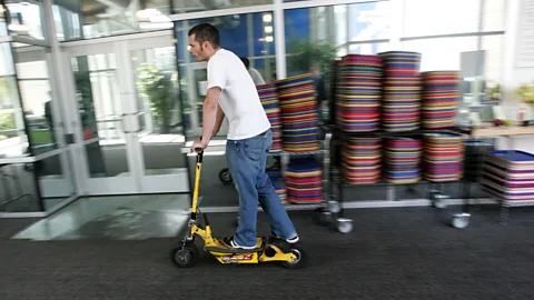 Getty Images A Google worker rides a Go-Ped scooter through the cafeteria (Credit: Getty Images)