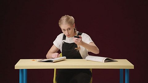 Girl sat at a desk setting her stopwatch before she starts her past paper.