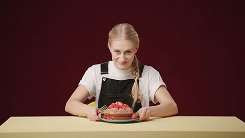 Girl sat at the table with a cake.