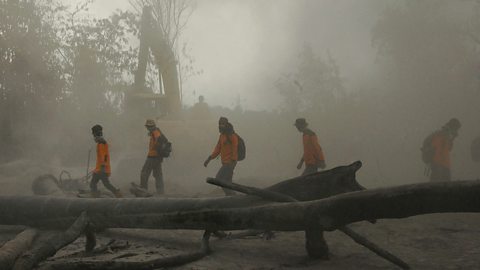 Members of a search and rescue team are covered in a cloud of volcanic ash from the Mount Merapi volcanic eruption.