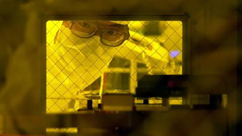 Getty Images A technician checks a 12-inch wafer in a dust-free room of UMC's fabrication plant in Tainan, before it is cut into pieces of microchip (Credit: Getty Images)