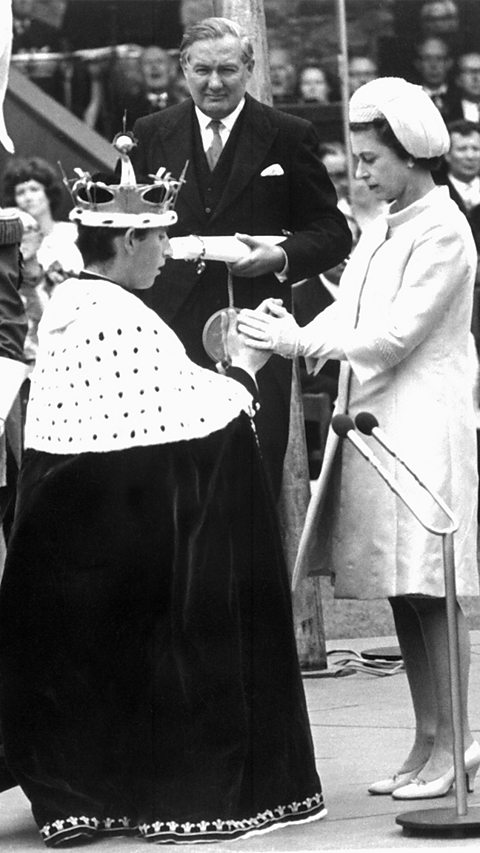 Queen Elizabeth II holds the hands of her 20-year-old son Prince Charles during his investiture as Prince of Wales, 1 July 1969, at Caernarfon Castle, Wales