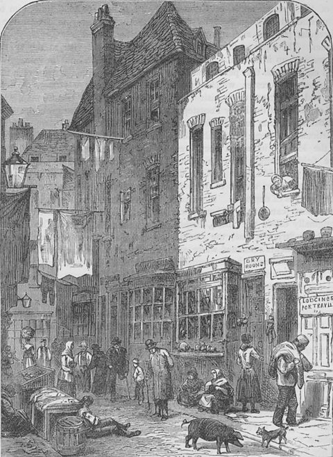 An illustration of St Giles rookery, London in 1850. Some people are walking in the street whilst others are lying on the floor next to a pig and a cat. Blankets are hanging from poles in the street