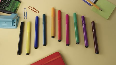 A set of coloured pens on a desk.