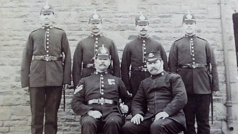 Grainy black and white photograph of six policemen posing for the camera wearing police uniform