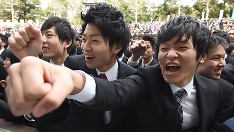 Toru Yamanaka/AFP/Getty Images Ready to work: young university students in Tokyo cheer at a ceremony kicking off the start of job hunting season in 2016 (Credit: Getty Images)