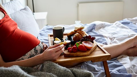 Pregnant woman eating in bed 