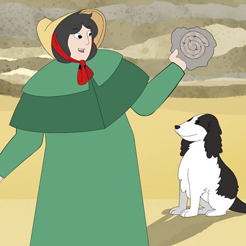 Mary Anning smiling holding a fossil on a beach, with her dog.