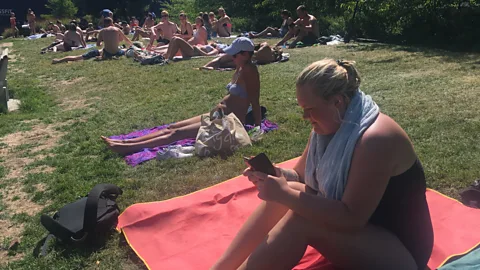 Maddy Savage Students sunbathing next to the Åkerselva river in Oslo, in Norway most public universities are free and there is easy access to loans (Credit: Maddy Savage)