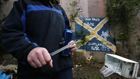 Getty Images A woman shows the knife she carries with her in Glasgow in 2005, the year the city was named Europe’s most violent (Credit: Getty Images)