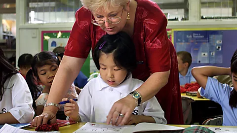 Getty Images An Australian primary school teacher teaches story writing skills to three students studying English as a second language (Credit: Getty Images)