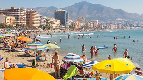 Buildings, sea and beach with people in Fuengirola