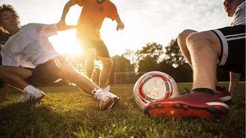 Teenagers tackling each other in football