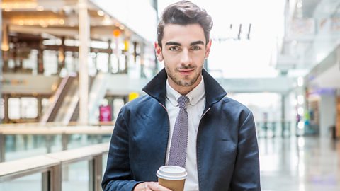 A man smiling holding a coffee cup